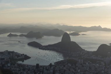 Beautiful landscape with a view to the Sugar Loaf bay area, the city and mountains seen from Christ the Redeemer Statue (Cristo Redentor) on top of Corcovado Mountain (Morro do Corcovado) during the sunrise in Rio de Janeiro, Brazil clipart
