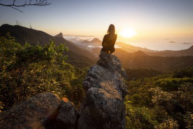 Yağmur ormanları, şehir ve dağ arkadaki Pedra da Proa Floresta da Tijuca (Tijuca Forest), Rio de Janeiro, Brezilya yılında görüldü gündoğumu tarafından kayalık kenarında Genç Yetişkin ile güzel manzara