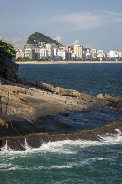 Paisaje de los edificios de la ciudad y el océano visto desde la costa rocosa — Foto de Stock