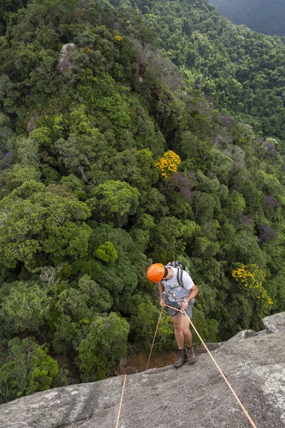 Jovem homem adulto rapel na rocha vertical sobre belo verde — Fotografia de Stock