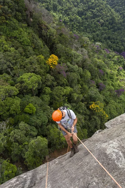 Ung vuxen man rappelling på vertikal klippa över vackra gröna — Stockfoto