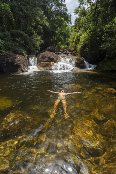 Beautiful rainforest waterfall with person floating in the water — Stock Photo, Image