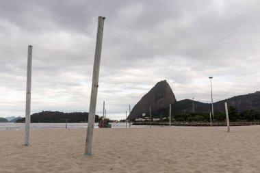 Boş bir Flamengo plajına güzel bir manzara. Cawid-19 Corona virüsü salgını sırasında kullanılmayan direklerle. Arkasında Sugar Loaf Dağı, Rio de Janeiro, Brezilya.
