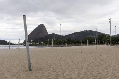 Boş bir Flamengo plajına güzel bir manzara. Cawid-19 Corona virüsü salgını sırasında kullanılmayan direklerle. Arkasında Sugar Loaf Dağı, Rio de Janeiro, Brezilya.