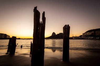 Güzel gün doğumu ışığı ve Sugar Loaf Dağı manzarası Botafogo Sahili, Rio de Janeiro, Brezilya 'da eski iskele kütükleri ile
