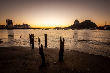 Güzel gün doğumu ışığı ve Sugar Loaf Dağı manzarası Botafogo Sahili, Rio de Janeiro, Brezilya 'da eski iskele kütükleri ile