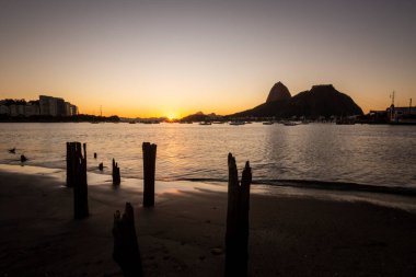 Güzel gün doğumu ışığı ve Sugar Loaf Dağı manzarası Botafogo Sahili, Rio de Janeiro, Brezilya 'da eski iskele kütükleri ile