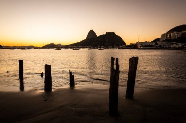 Güzel gün doğumu ışığı ve Sugar Loaf Dağı manzarası Botafogo Sahili, Rio de Janeiro, Brezilya 'da eski iskele kütükleri ile