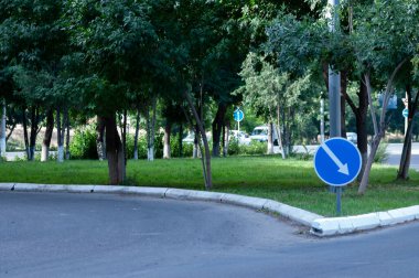 Sokak, mavi yuvarlak tabela ve beyaz ok dönüşü gösteriyor. Beyaz oklu yuvarlak yol işareti.