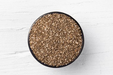 Chia tohum yuvarlak dökme demir Kupa Beyaz ahşap zemin üzerinde görüntülemek doğrudan yukarıda.