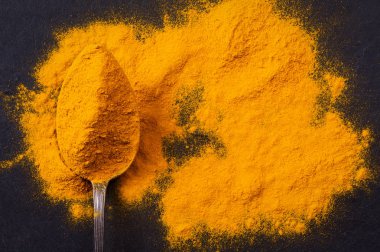 Curcuma zerdeçal baharat toz siyah arduvaz arka planda