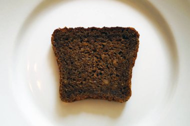 beyaz bir tabak üzerinde siyah kahverengi çavdar ekmeği