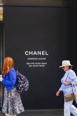 Yan duvarında marka logosu olan Chanel mağazası ve yanından geçen insanlar.