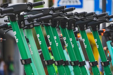 Bir paylaşım istasyonunda birkaç yeşil renkli hareket kabiliyeti olan elektrikli scooter bir araya geldi.