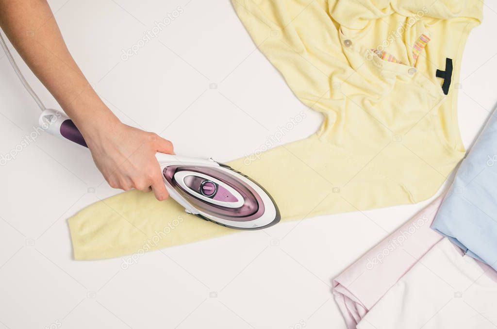 Woman hand with iron ironing clothes, top view