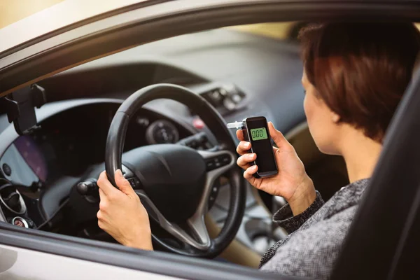 Vrouw met behulp van adem alcohol analyzer in de auto — Stockfoto