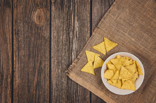 Heap of potato chips in bowl on wooden table background — Stock Photo, Image