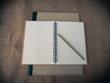 Vintage tarzı. Binder, açık defter, kalem ve çuval bezi arka plan ile organize masası