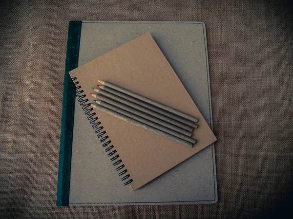 Vintage style. Organized desk with binder, closed notebook, pencils and burlap background