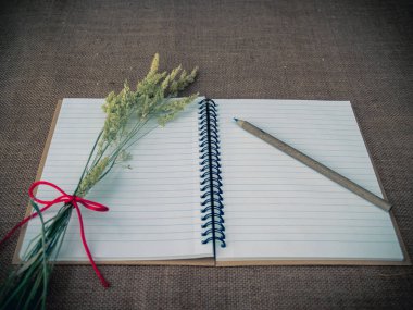 Vintage tarzı. Açık defter, Kuru ot, kalemler ve çuval bezi arka plan ile organize masası