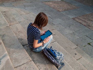 Bir tablet bir üniversitede bir üniversite kampüsü merdivenlerde genç bir kadınla