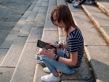 Bir tablet bir üniversitede bir üniversite kampüsü merdivenlerde genç bir kadınla