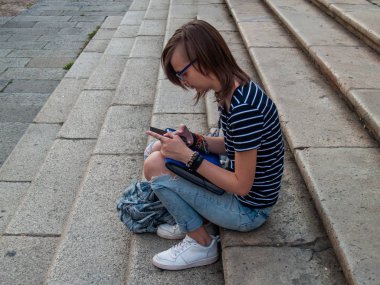 Ellerini historial bir bina merdivenlerde bir akıllı telefon olan genç bir kadın