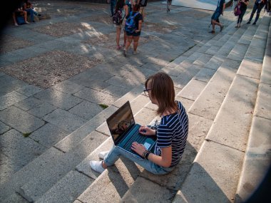 Bir üniversitede bir üniversite kampüsü merdiven üstünde a laptop ile okuyan bir genç kadın