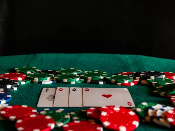 Dört as poker destesi ve yeşil bir hasır üzerinde çeşitli renklerin poker fişleri