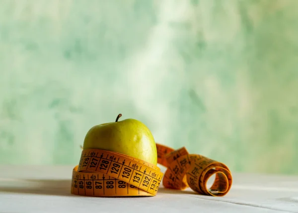 Obezite kavramı. Yeşil elma ve bir masa üstünde bir şerit metre