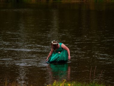 Bir nehir neşeli bir genç kadının portresi ile bir yeşil parti elbise giymiş