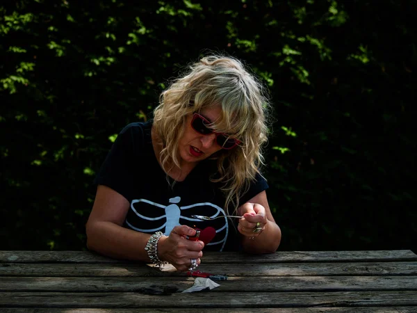 A woman preparing a dose of drug with a lighter and a spoon and a dose of drug next to it on a wooden table
