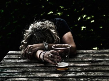 Bir bardak bira bir masanın üzerine eğilerek onun elinde, bilinci yerinde, sarhoş bir kadınla