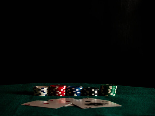 Четыре туза колоды для покера и фишки для покера различных цветов на зеленом коврике
