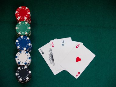 Dört as poker destesi ve yeşil bir hasır üzerinde çeşitli renklerin poker fişleri