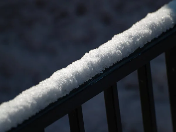 snow on fence on winter day, close up