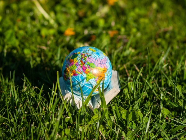 globe on book on green grass  outdoors