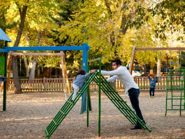 Baba ve yakışıklı çocuk oyun parkında