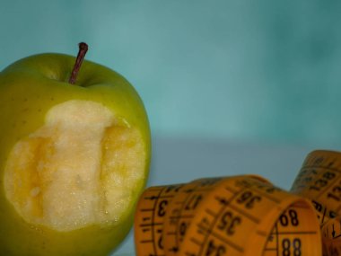 Obezite kavramı. Bir dolu yeşil elma ve bir masa üstünde bir şerit metre