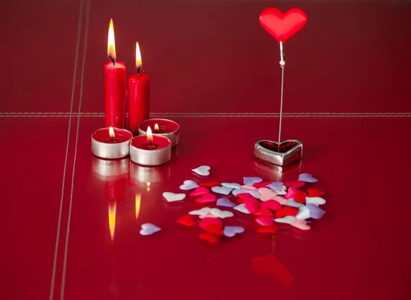 Concept of love Red candles lit and a lot of hearts with a red background