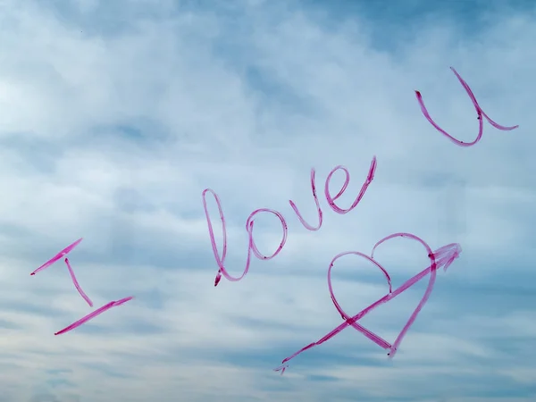 Concept of love The word love written with rouge lipstick on a window with clouds and blue sky