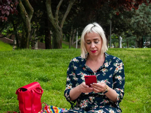 Donna Utilizzando Smartphone Mentre Seduto Sul Prato Immagine Stock