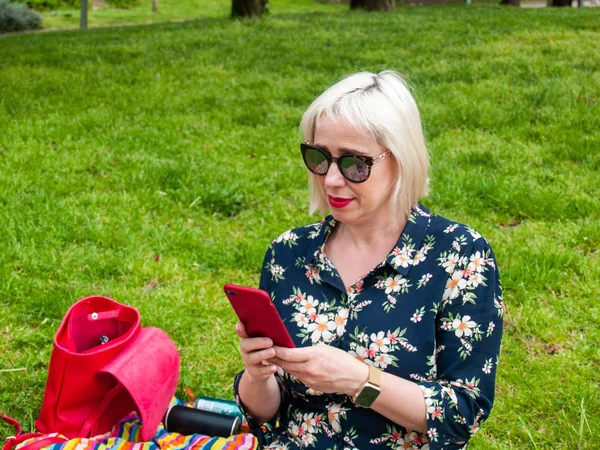 Donna Utilizzando Smartphone Mentre Seduto Sul Prato Immagine Stock