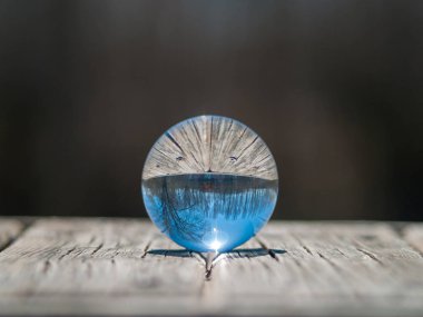Ahşap masada bir kristal top açık gökyüzü yansımaları        