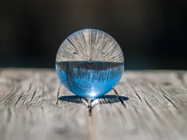 Reflections of clear sky in a crystal ball on a wood table