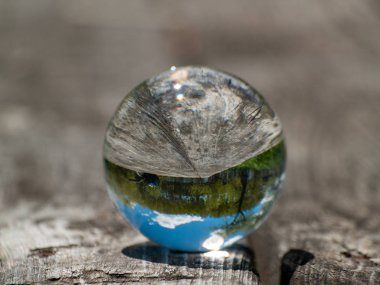Ahşap masada bir kristal top açık gökyüzü yansımaları        