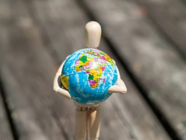 wooden mannequin with a world ball in his arms. Ecology concept, globalization