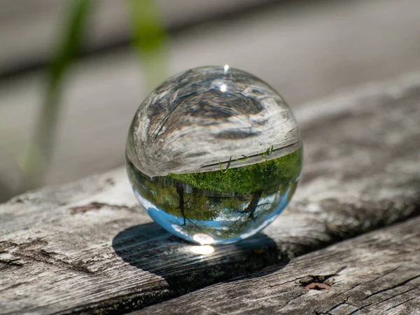 Reflections of clear sky in a crystal ball on a wood table