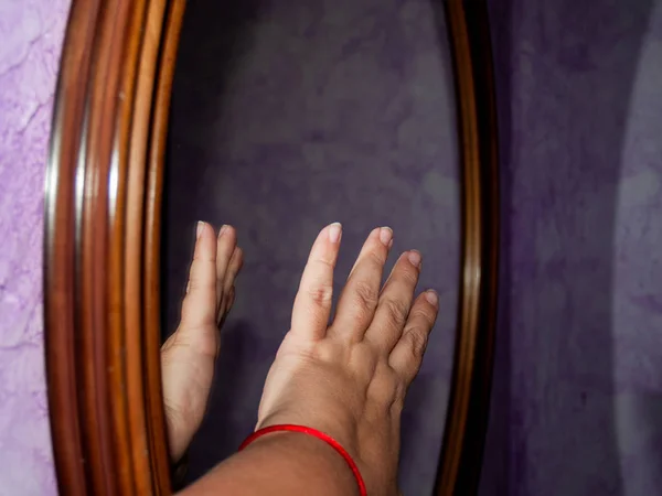 female hand on mirror and reflection