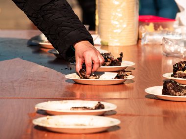 Tanınmayan kişi üzerinden İspanya bir köyde popüler bir partide sokakta bir kağıt tabak pişmiş et alarak